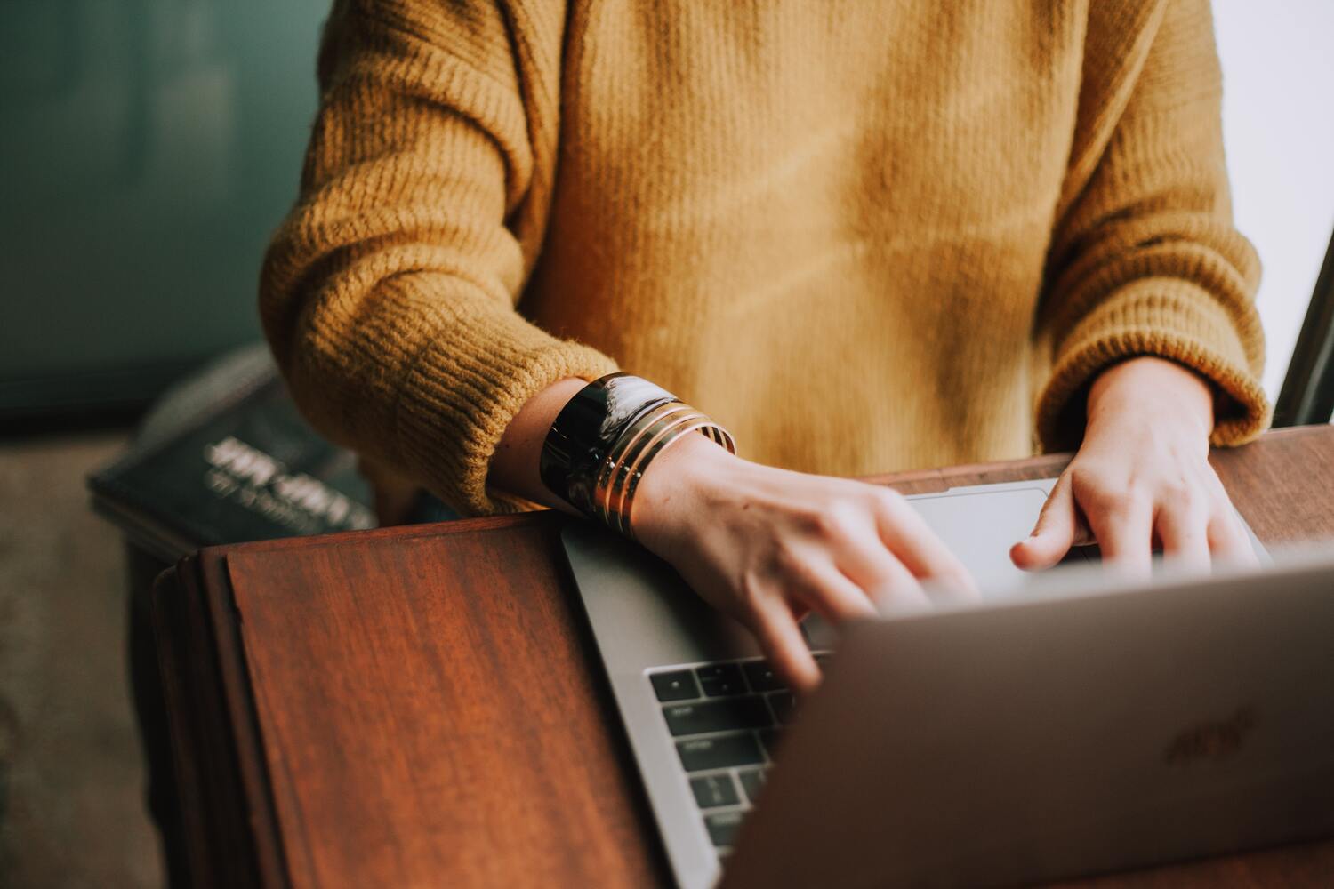 A Woman In A Golden-brown Sweater Researching Online.