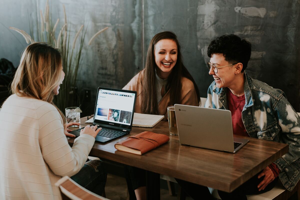 Three Laughing Employees Sitting At A Table And Brainstorming How To Measure Workplace Culture