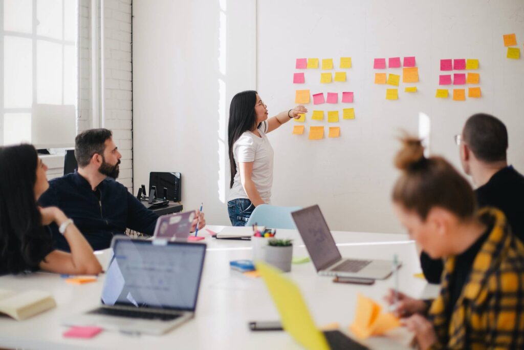 A woman leading a discussion in a conference room, using sticky notes to brainstorm