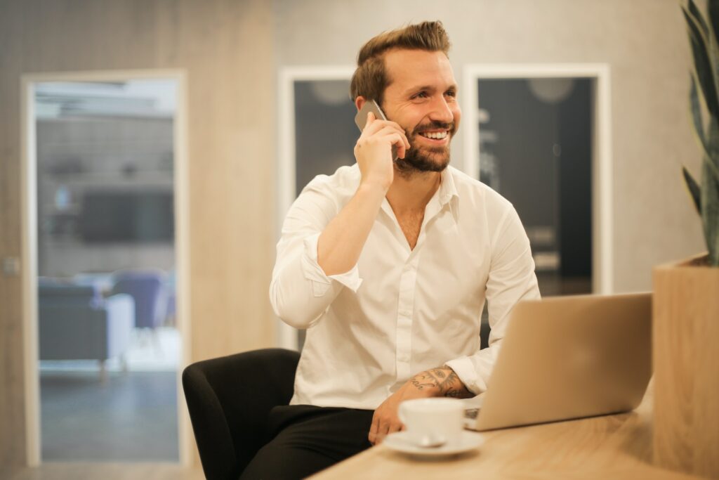 A man completing human resource manager education requirements at his computer while on the phone