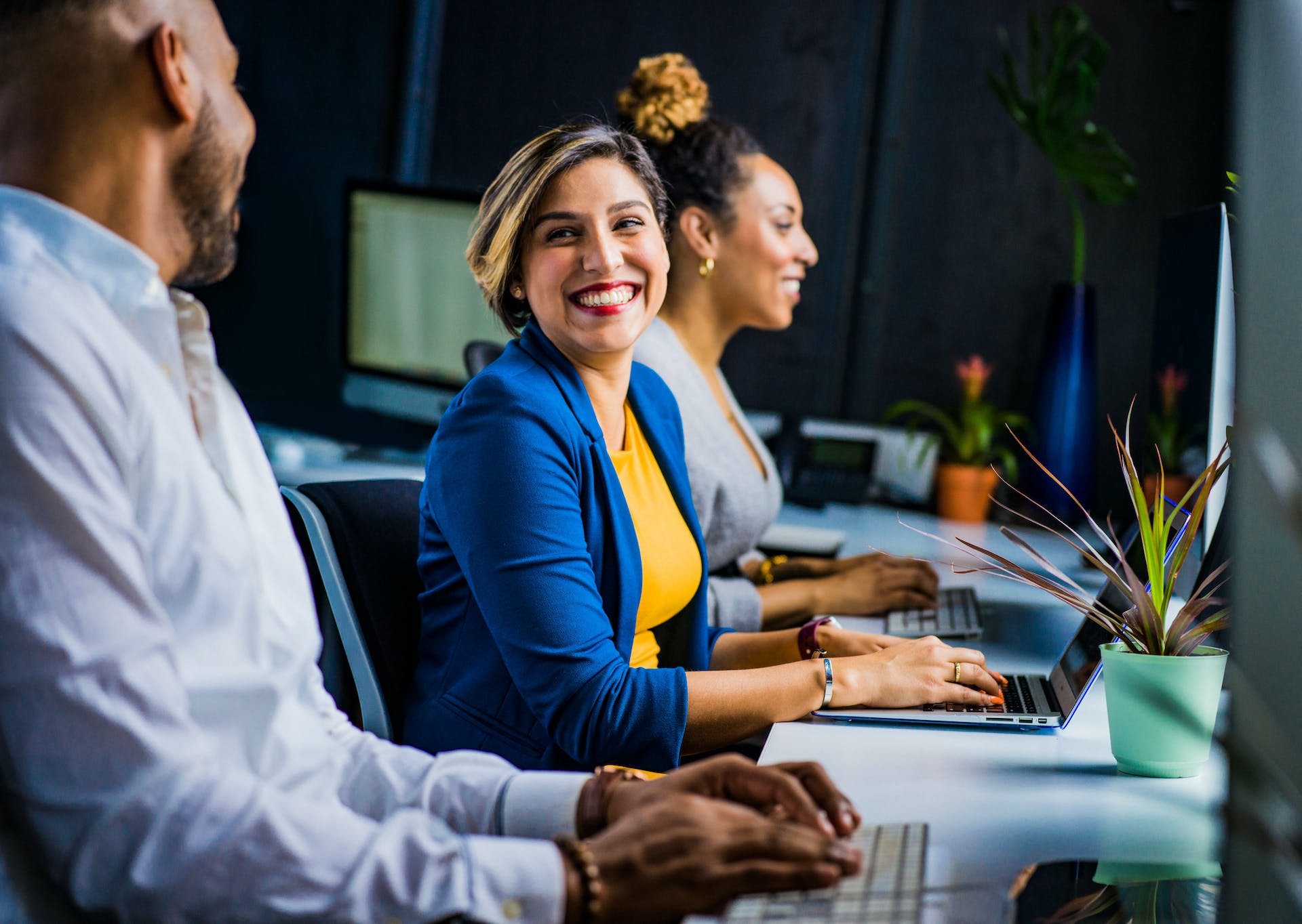 A Woman Smiling While Working At Her Desk Measuring Workplace Culture