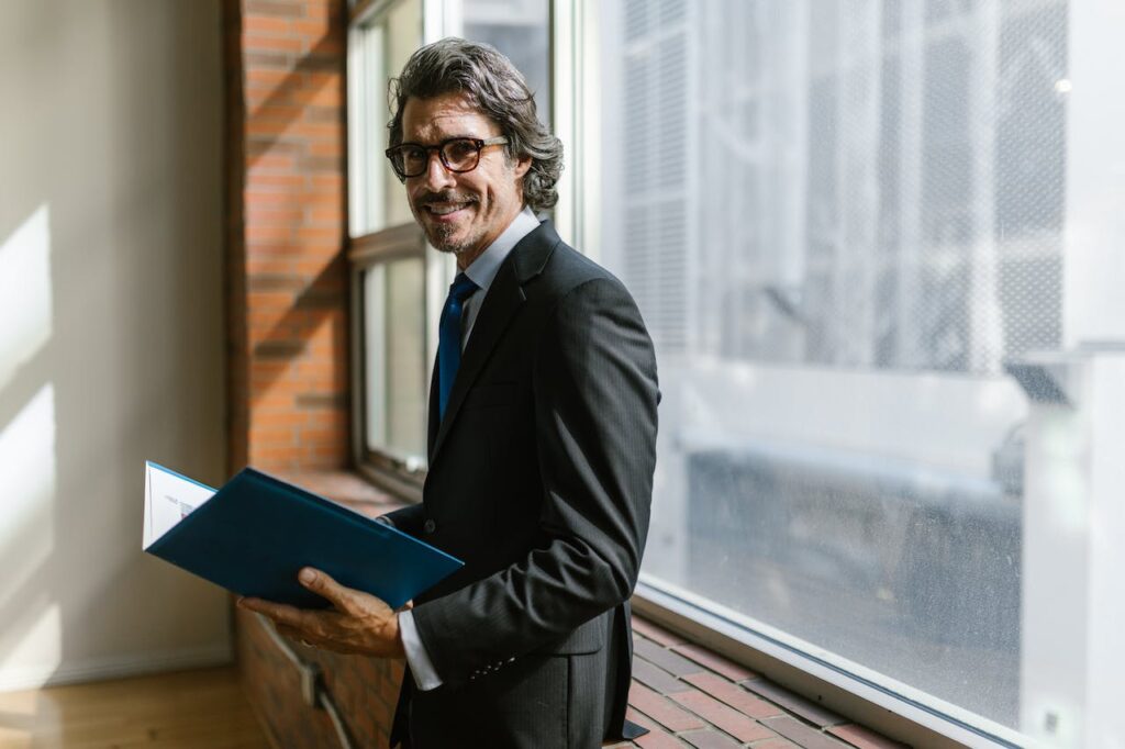 A man on a CHRO journey smiling wearing business attire while holding a folder