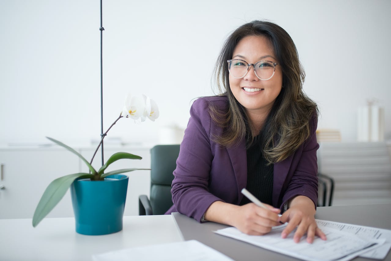 A Professional Woman With Human Resource Manager Job Responsibilities Sitting At An Office Desk With Papers