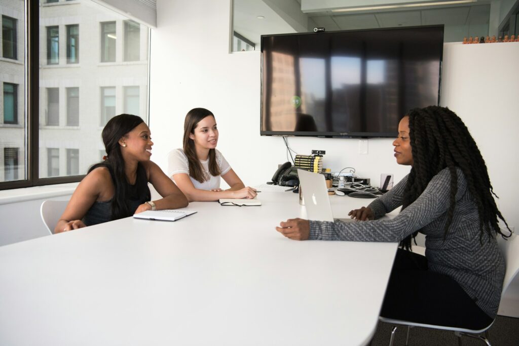 Three women completing online HR certification courses on a laptop