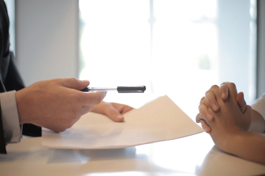 A person handing over pen and paper in an entry level HR job interview