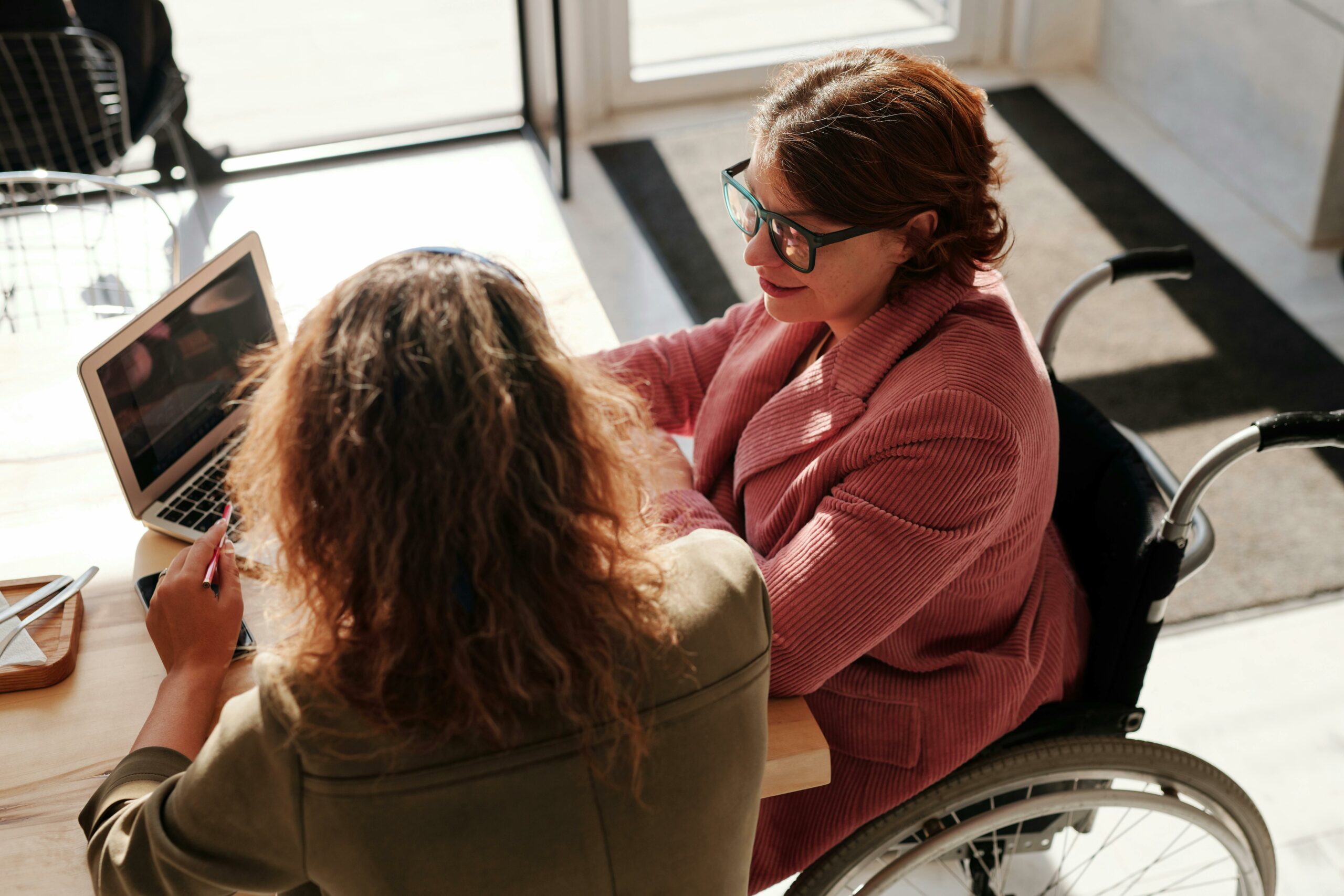 Two Women Working At A Laptop Discussing AI