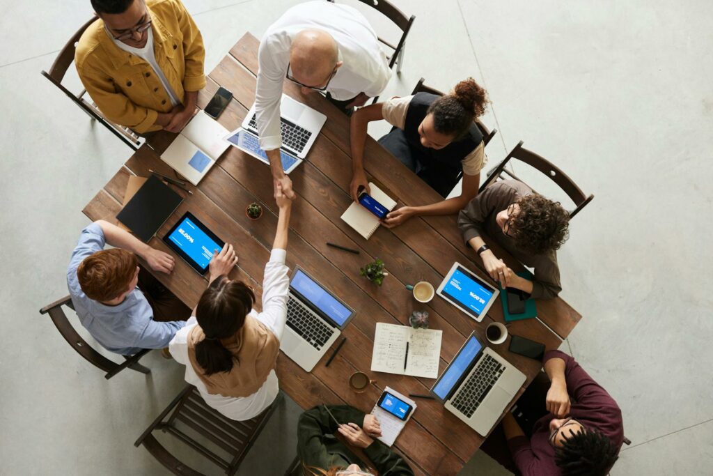 A group of people working around a table on different devices