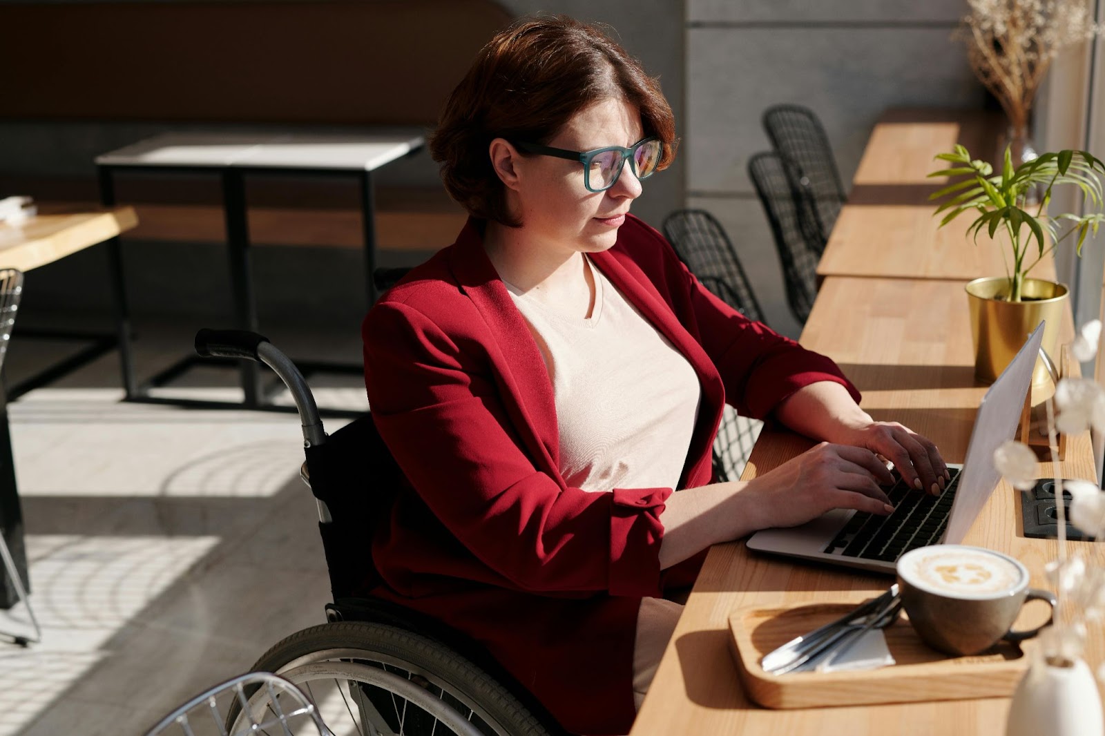 A woman taking the “Mastering Microsoft Copilot” course from HREN in a shared workspace with a cup of coffee