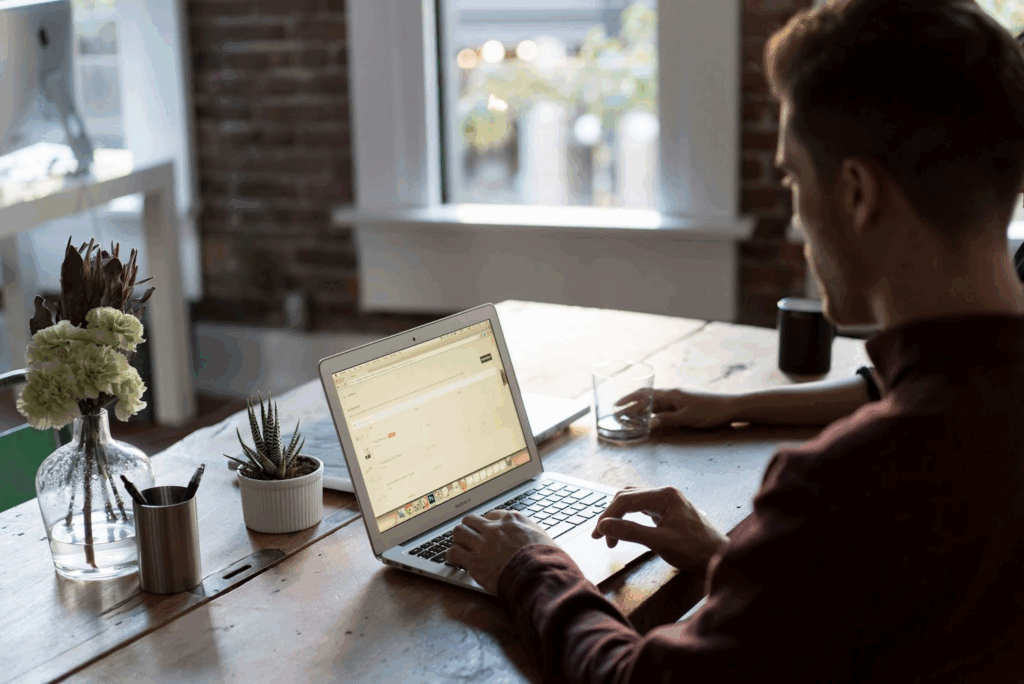 A man learning about HR compensation at his laptop with plants on the table